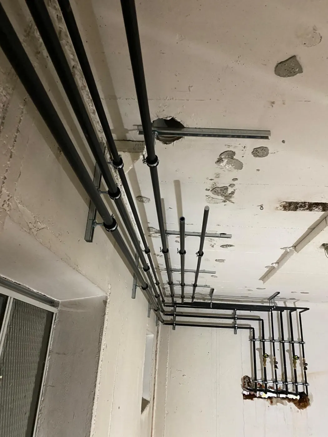 Neu verlegte Rohrleitungen an der Kellerdecke mit Montageschienen