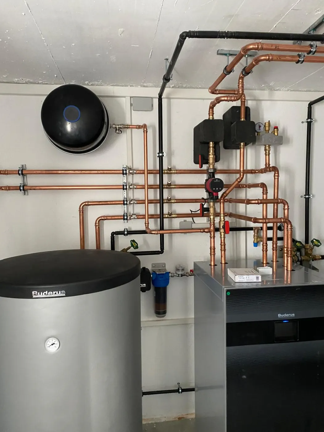 Installierte Wärmepumpe mit Warmwasserspeicher und Kupferverrohrung im Heizungsraum